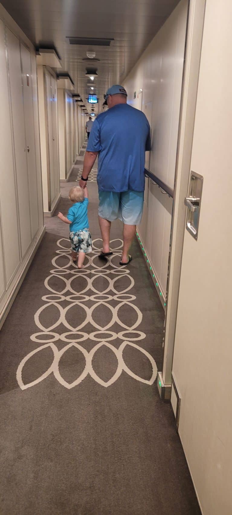 Man and little boy walking down the hall of a cruise ship