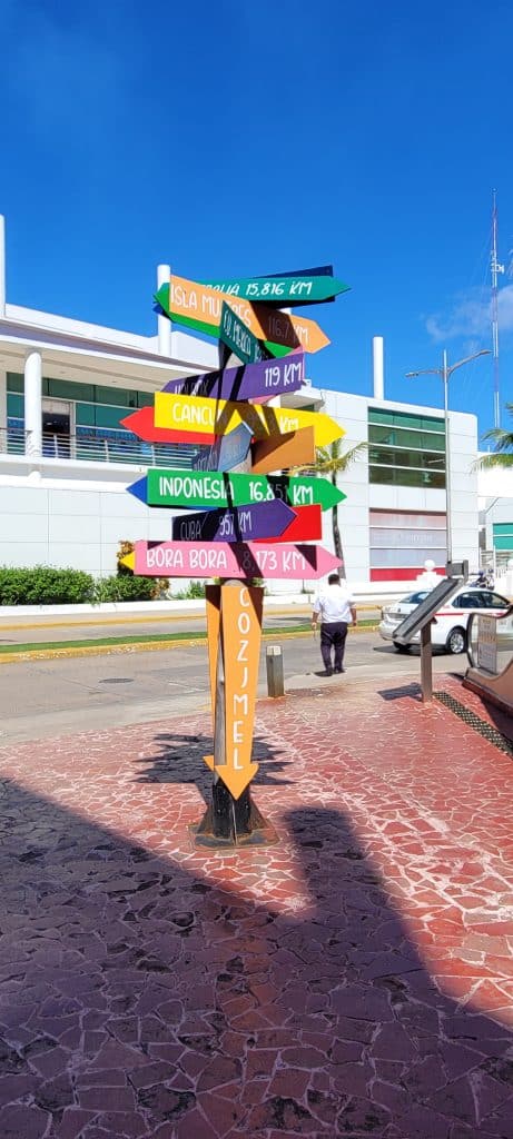 Post with colorful city signs and distances on it