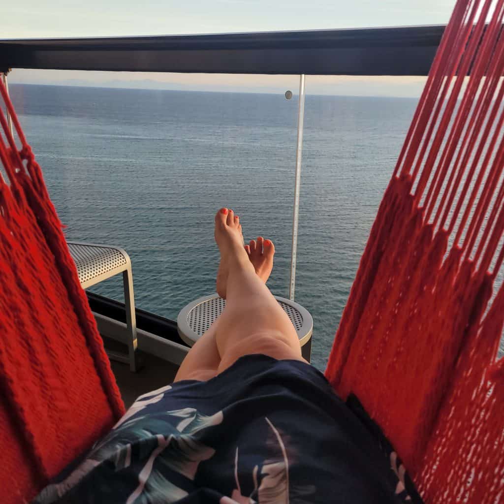 Picture of the bottom half of a woman laying in a hammock on a cruise ship balcony