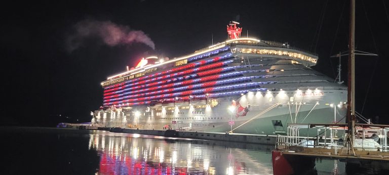 Virgin Voyages' ship, Valiant Lady at night with St. John's lit up on the side of the ship