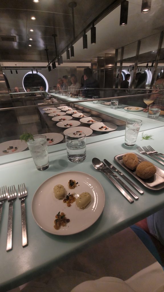 Plates of food being prepared at The Test Kitchen Restaurant experience on Virgin Voyages Cruises