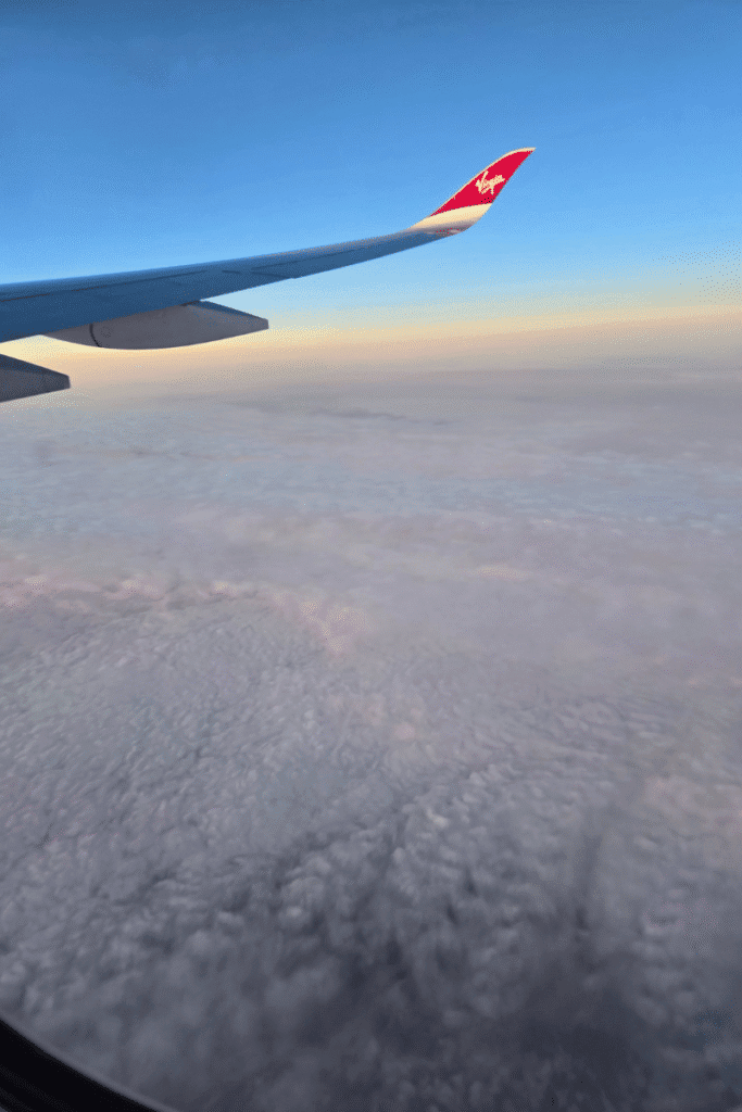 View of an airplane wing over the clouds during a flight to Europe for a cruise vacation.
