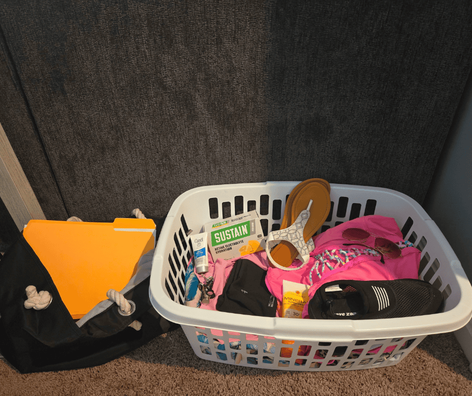 Cruise prep pre-pack pile in a laundry basket with swimsuits, flip-flops, and cruise essentials set aside before packing.