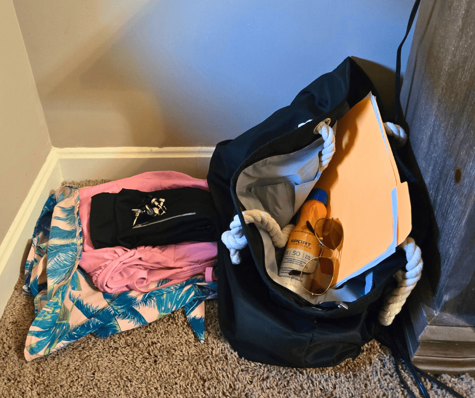 Cruise prep corner pile with clothes and a travel bag set aside for embarkation day before packing for a cruise.