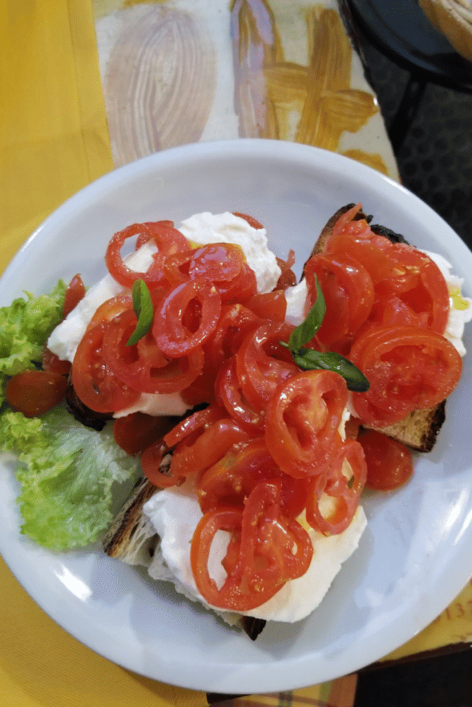 Fresh tomato and mozzarella dish in Italy, highlighting summer flavors cruisers can enjoy when sailing Europe in season.