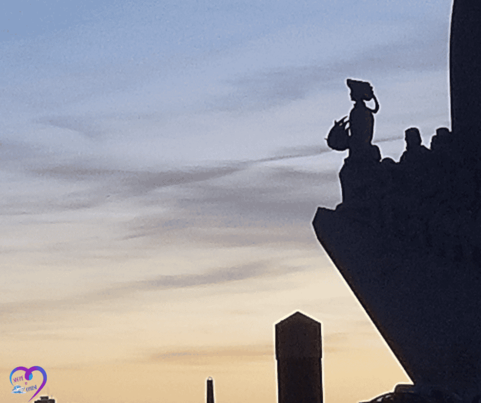 Statue silhouette at sunset over Lisbon harbor, creating a reflective mood for traveler Q&A.