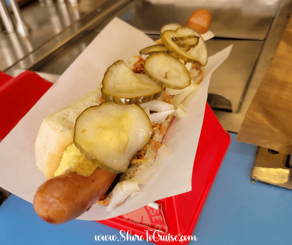 Traditional Danish Rød pølse hot dog topped with onions, pickles, and remoulade in Copenhagen.
