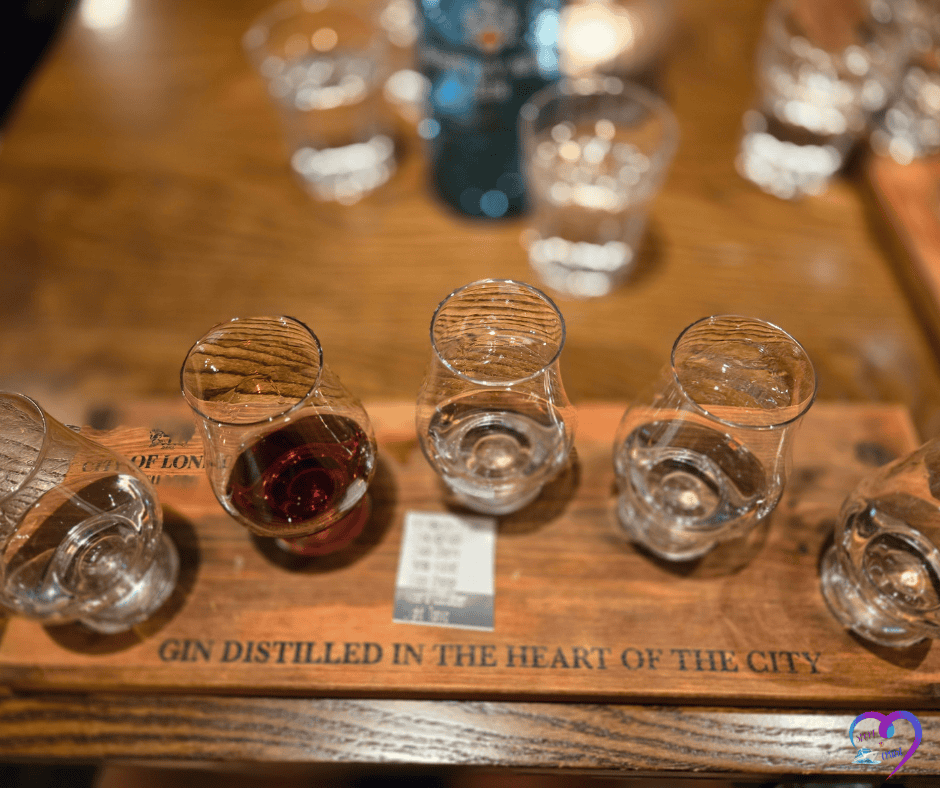 Gin tasting flight with small glasses on a wooden board labeled ‘Distilled in the Heart of the City.