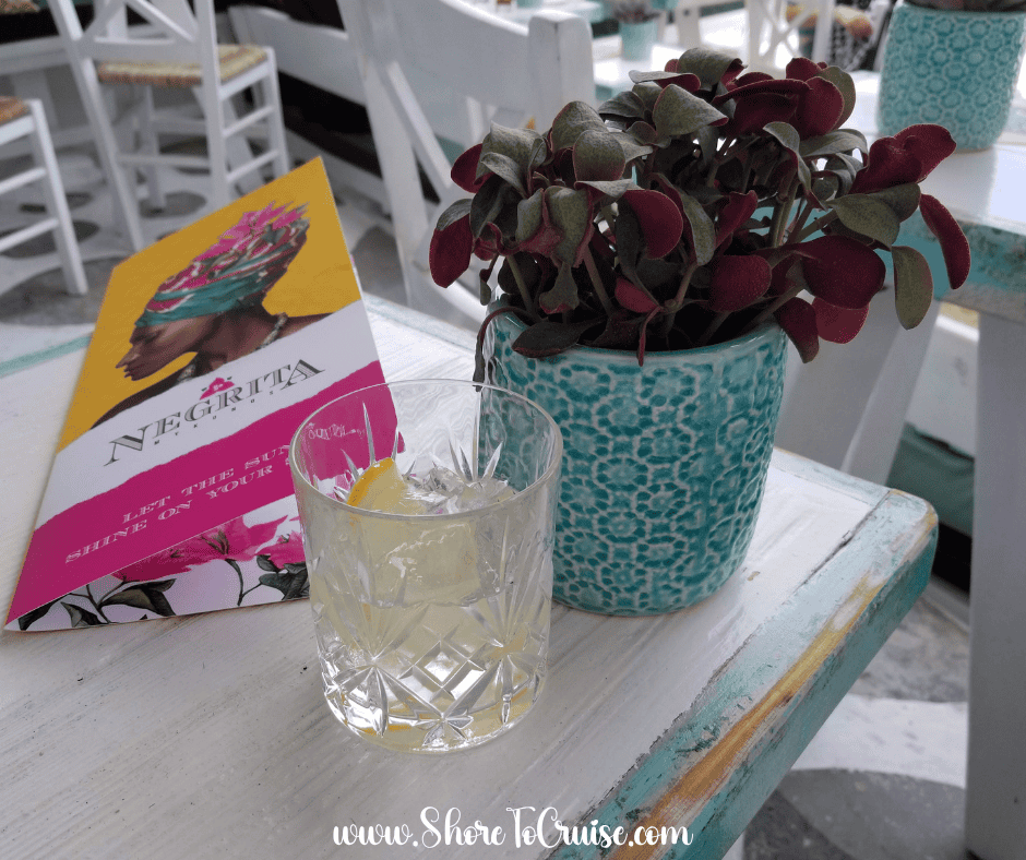 Mediterranean cocktail and Negrita menu on a turquoise café table — casual and stylish evening cruise vibes.