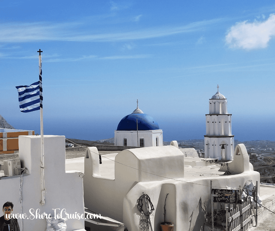Santorini rooftops and blue-domed churches under a bright sky — ideal for light, breathable cruise outfits in the Mediterranean sun.