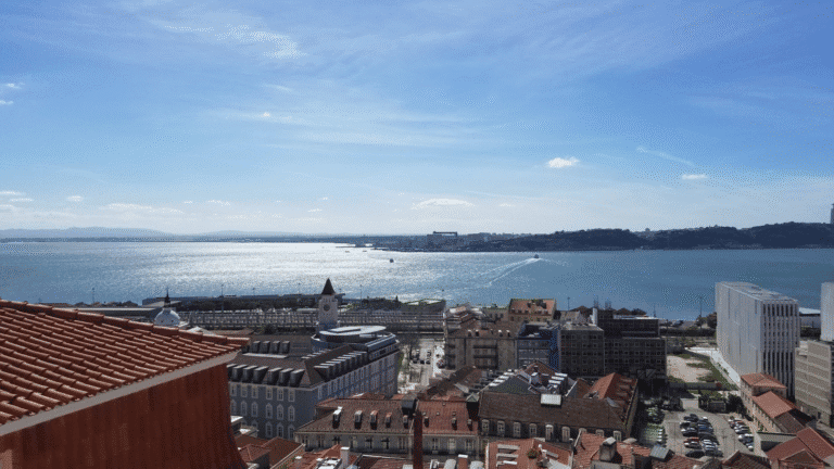 Scenic view of Lisbon’s rooftops and harbor under a sunny blue sky, symbolizing European cruise adventures.