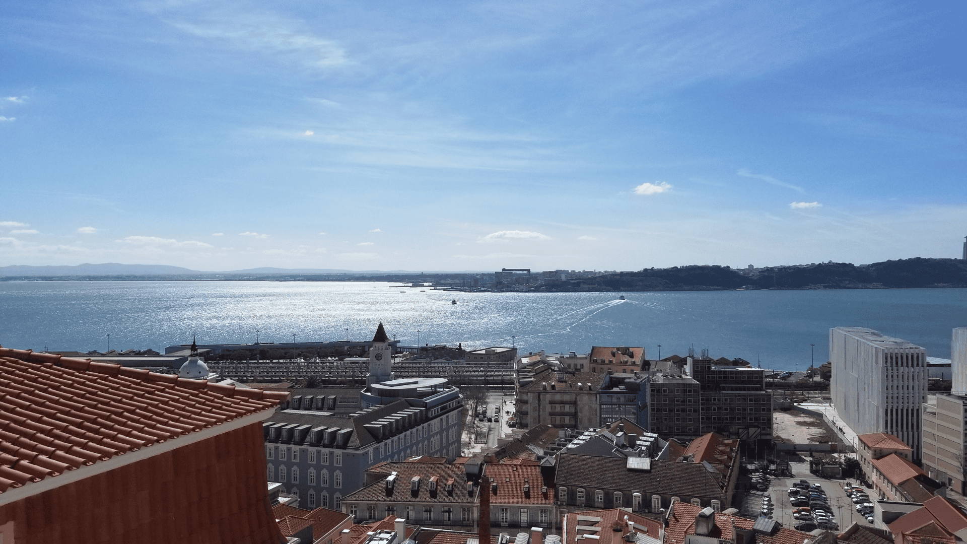 Scenic view of Lisbon’s rooftops and harbor under a sunny blue sky, symbolizing European cruise adventures.