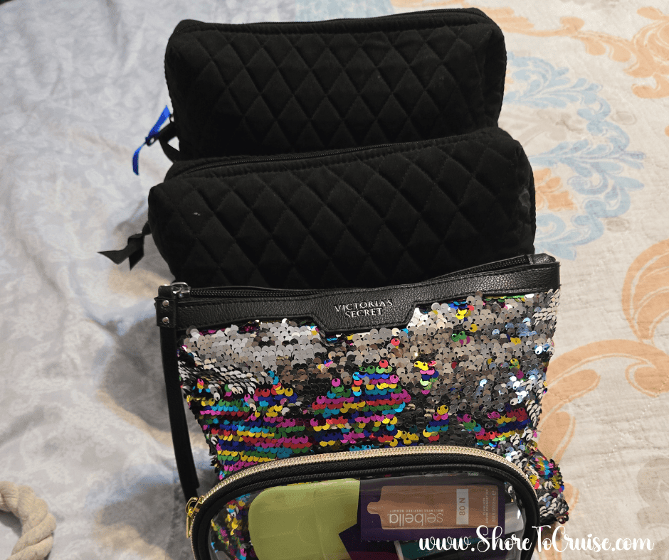 Stack of travel bags including black quilted and sequin cases used to organize cruise first aid supplies